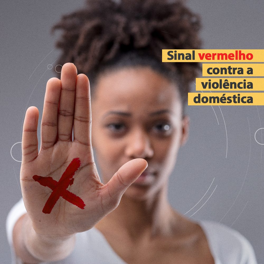 Mulher com a palma da mão erguida, marcada com um X vermelho, ao lado do título da campanha Sinal Vermelho contra a violência doméstica.
